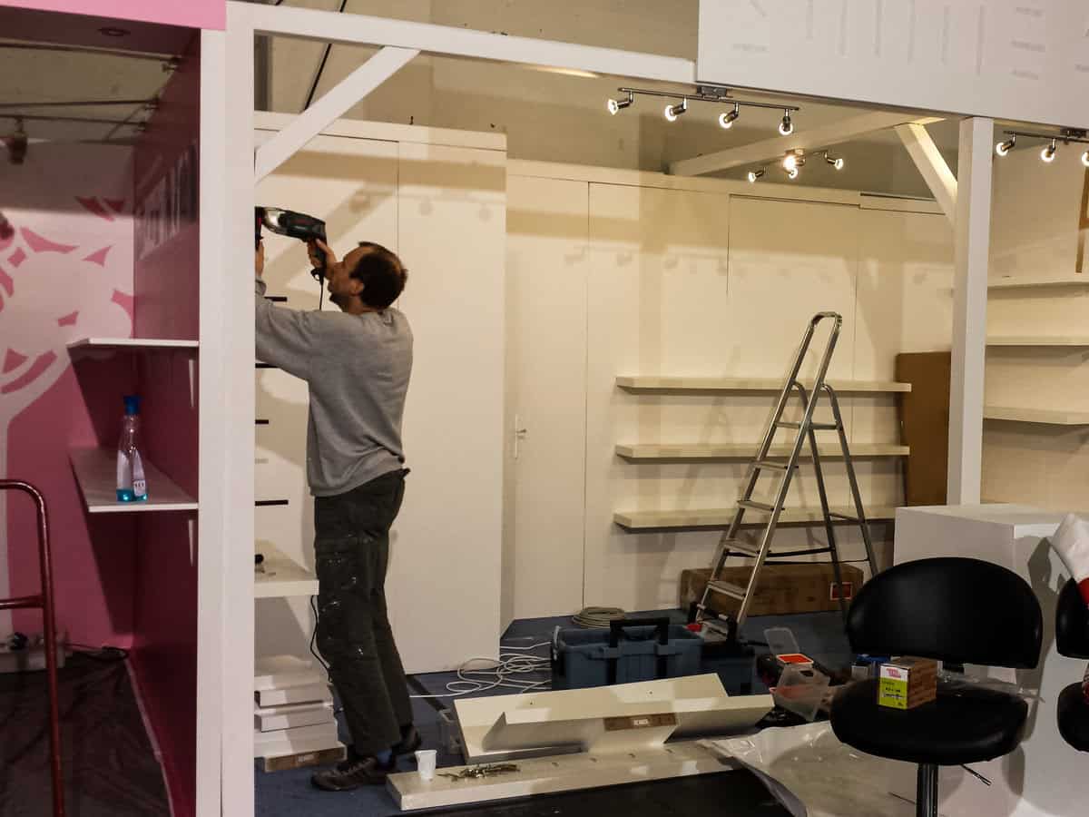 Trade fair setup: Company founder drilling to finish booth on time
